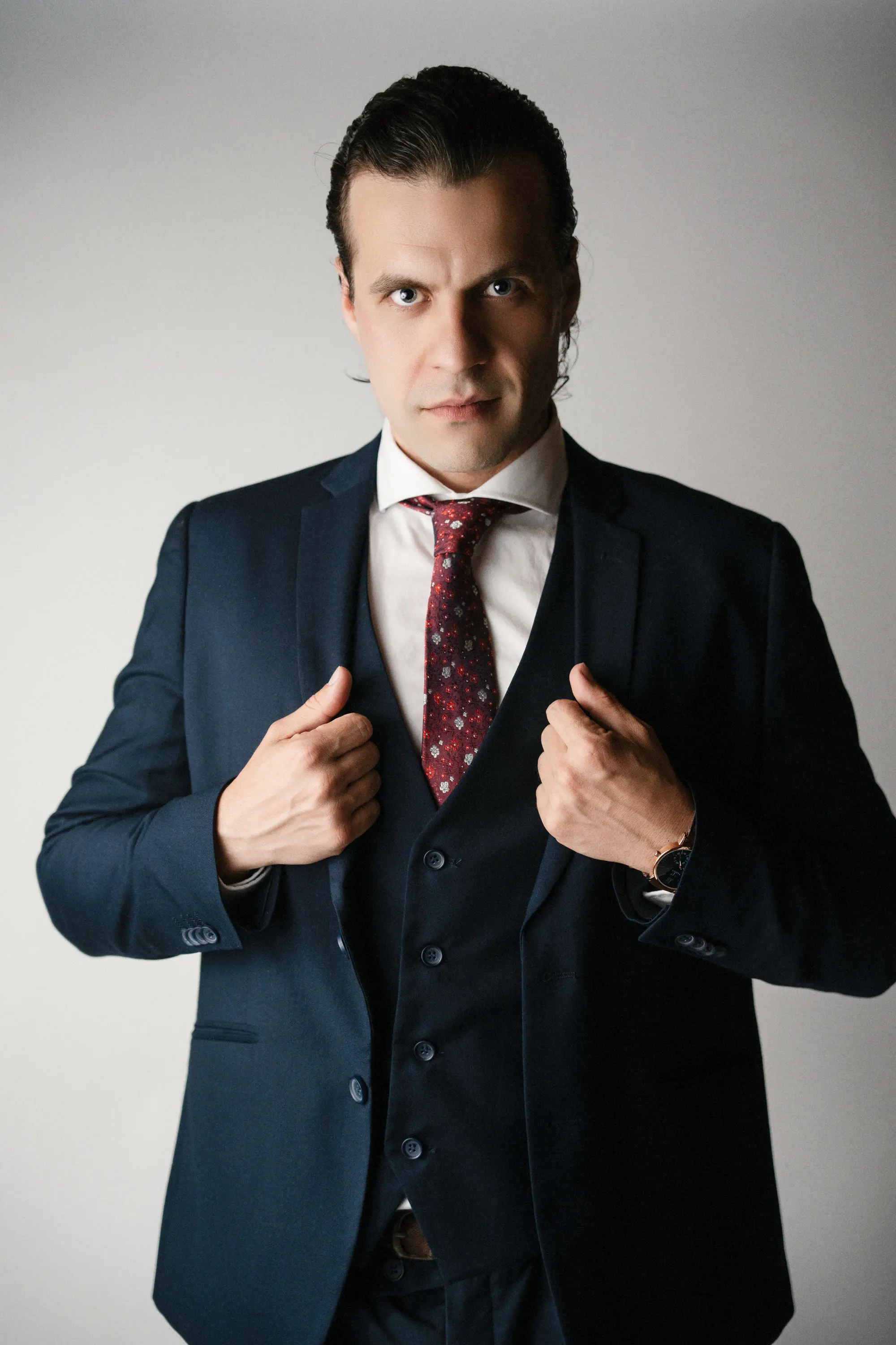 Jacobo Abellás de cuerpo entero con traje azul marino y corbata granate