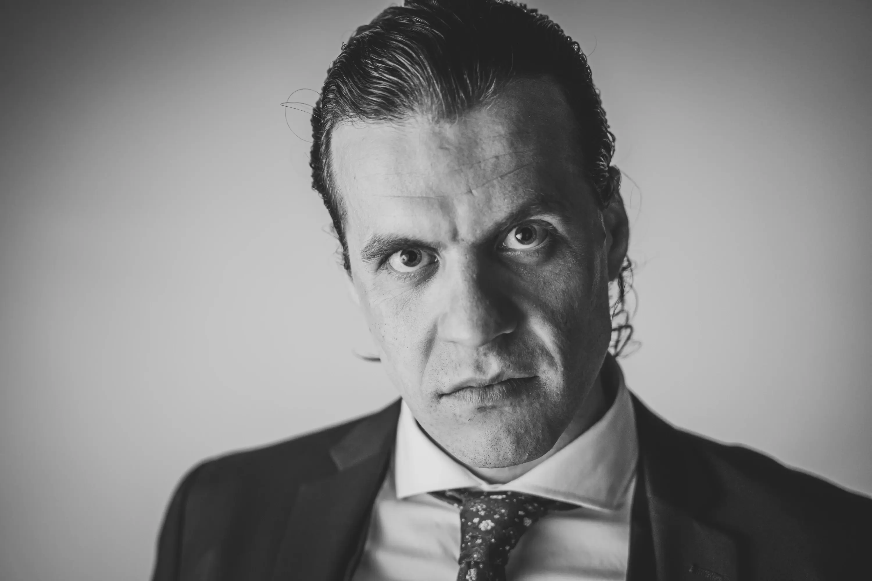 Retrato de personaje en blanco y negro de Jacobo Abellás con traje y mirada amenazante